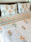 Orange Floral and Green Leaf hand-block dohar styled on a bed, showing the ivory ground and floral border.