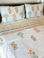 Orange Floral and Green Leaf hand-block dohar styled on a bed, showing the ivory ground and floral border.
