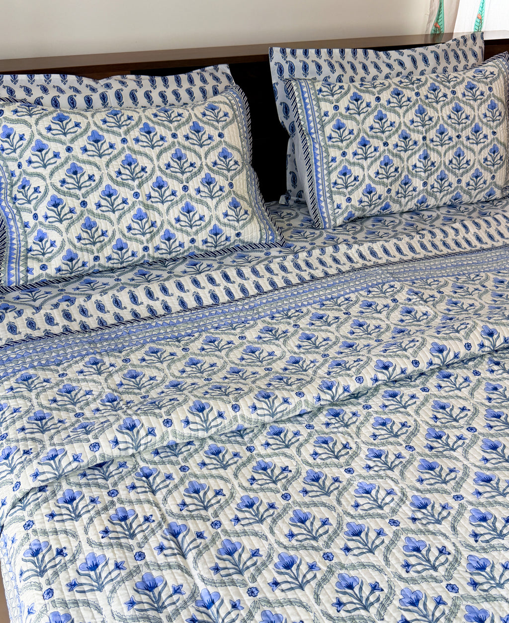 Blue Floral Butta pure mulmul quilted bedcover styled on a bed.